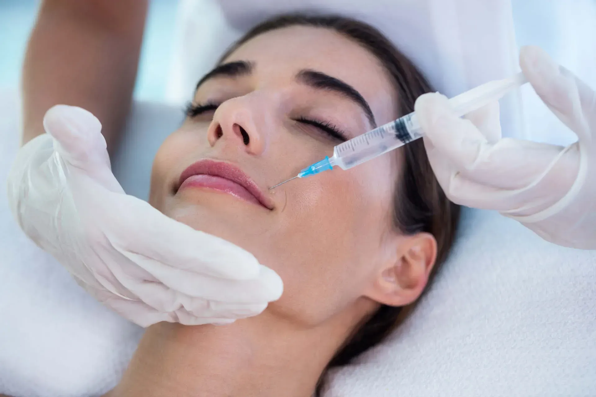 Woman receiving cosmetic injectable treatment on face.