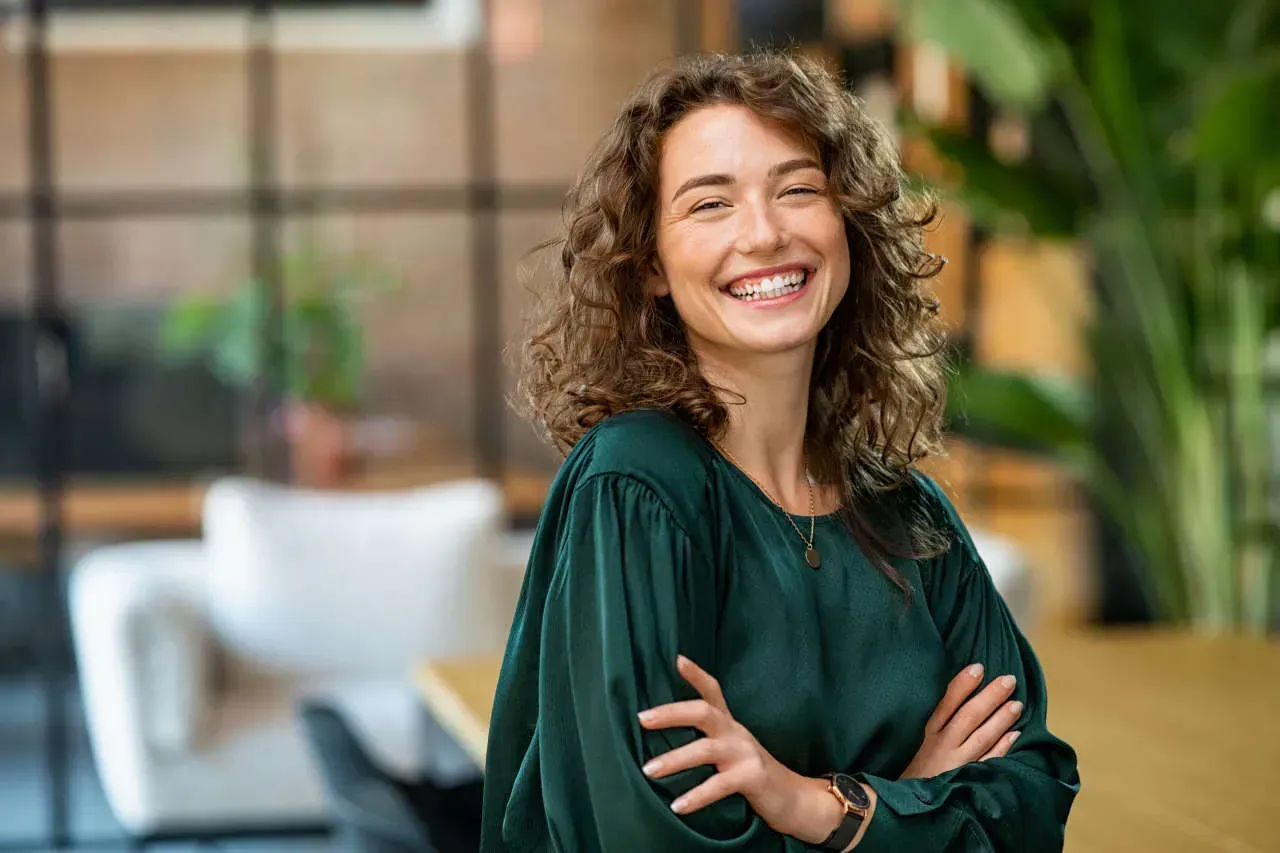 Smiling woman with curly hair in green blouse.