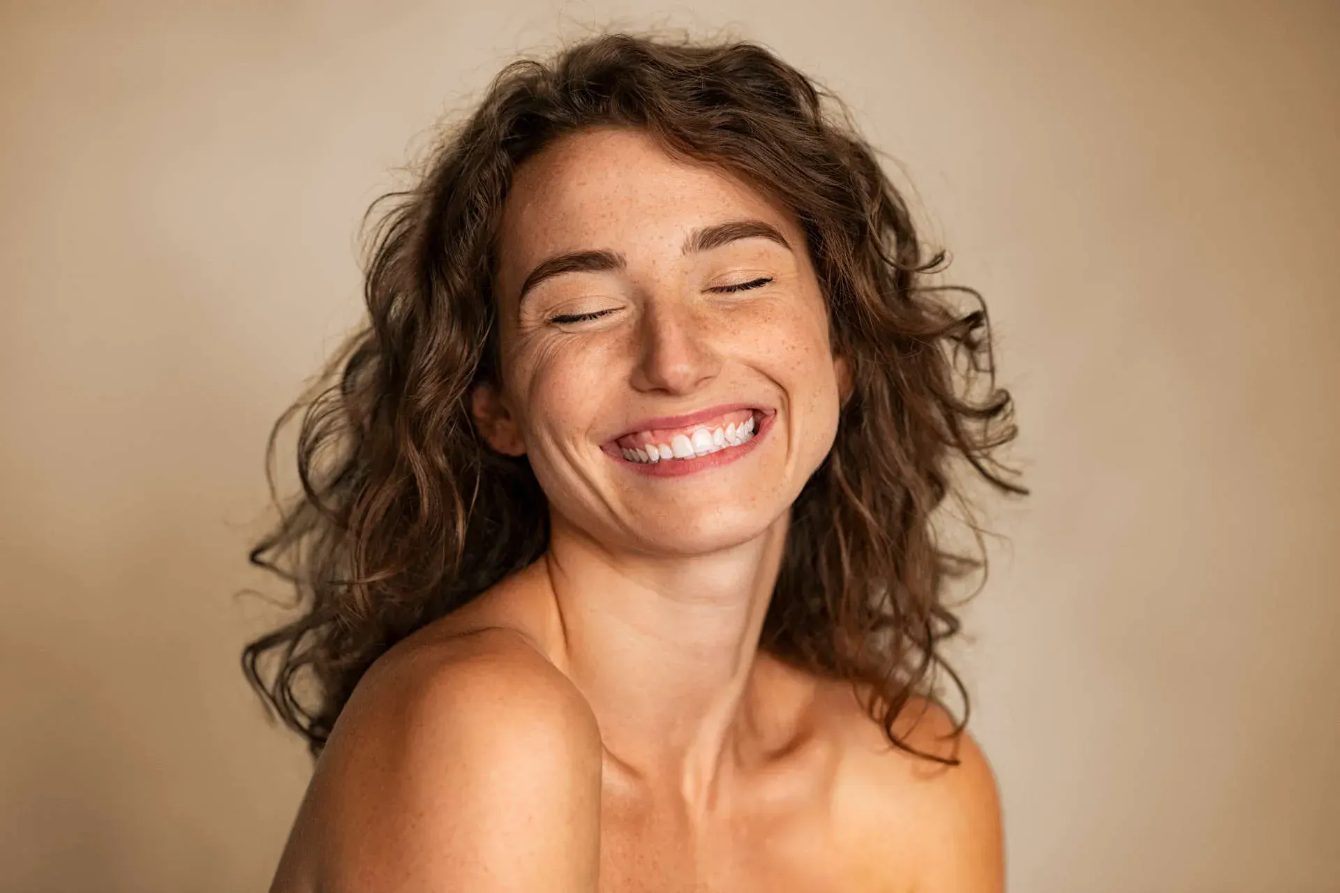 Smiling woman with curly hair and closed eyes