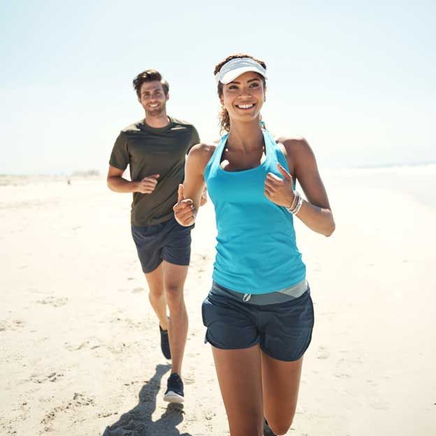 Couple jogging on the beach during daytime.