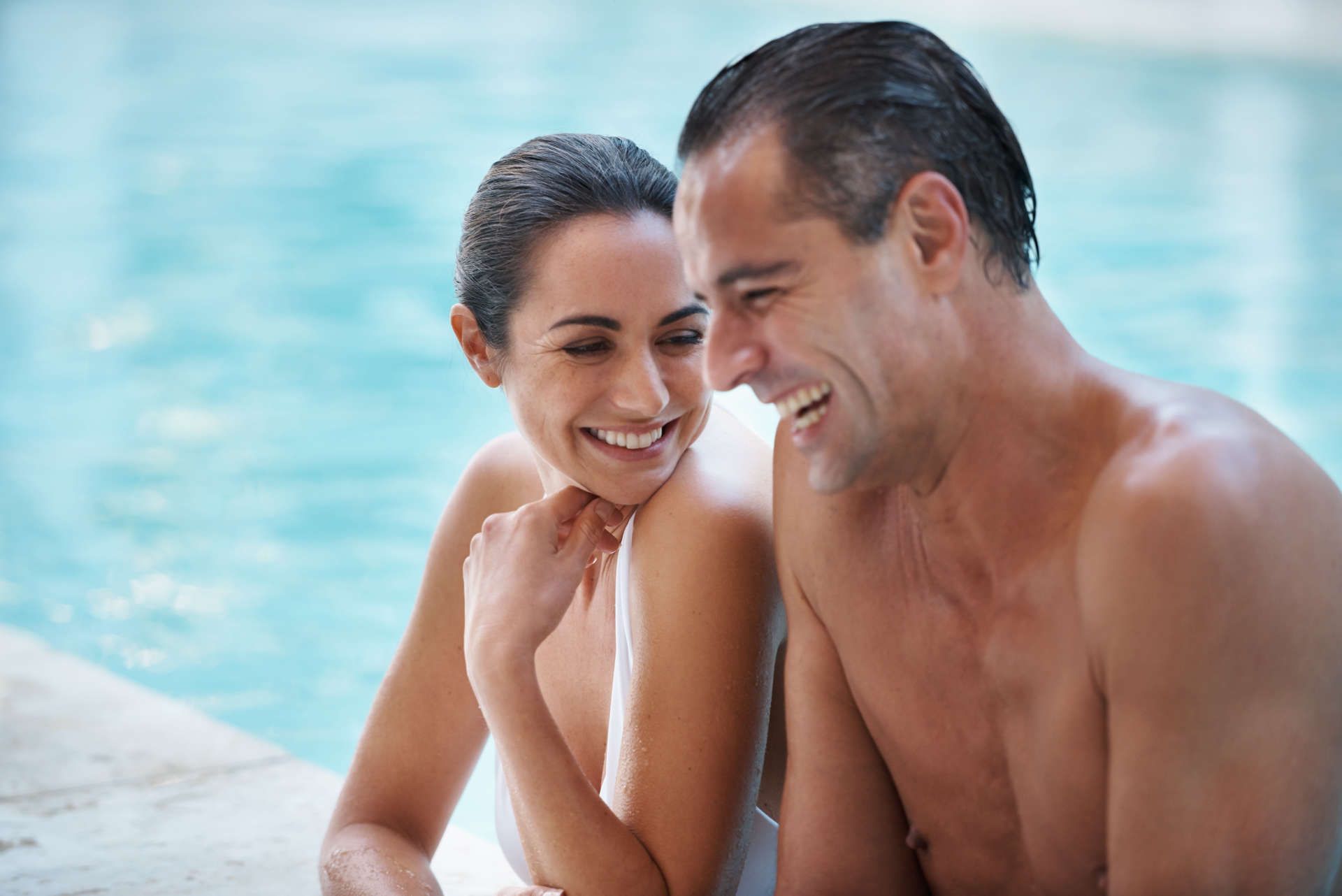 Couple laughing by the poolside.